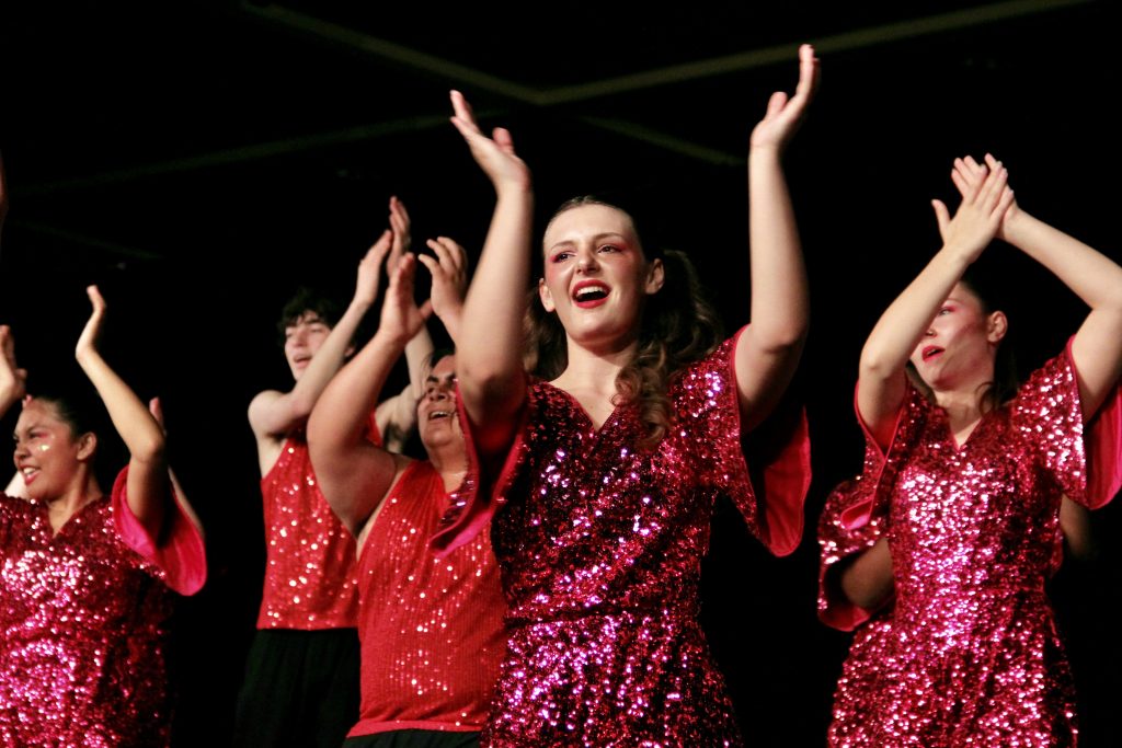 show choir students in sparkly pink and red costumes performing