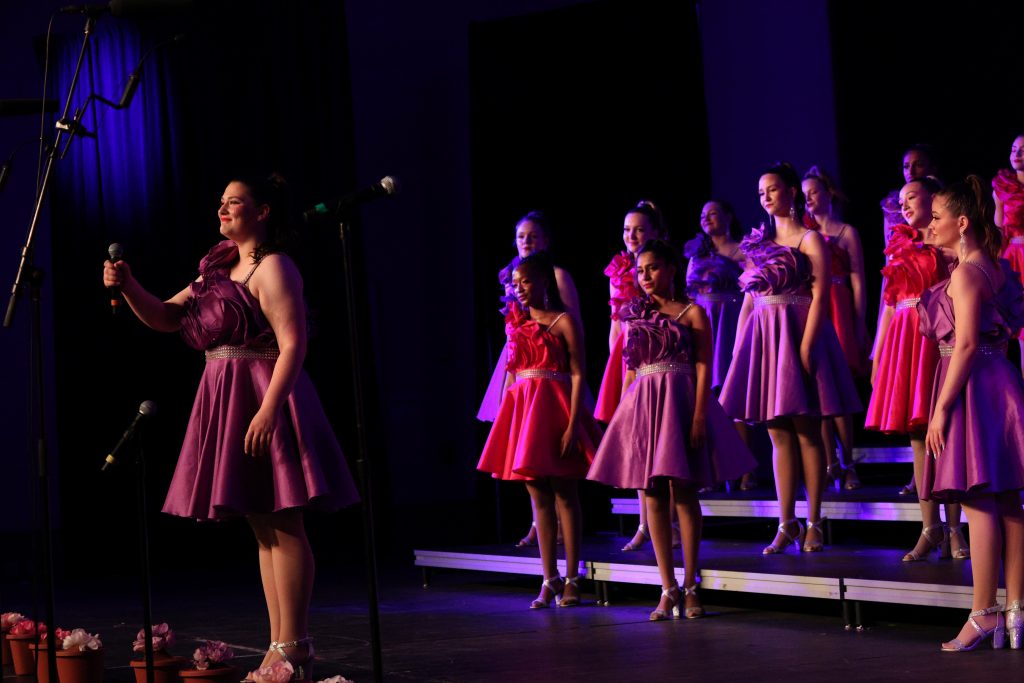 Olentangy High School She-Notes performing on stage in vibrant dresses