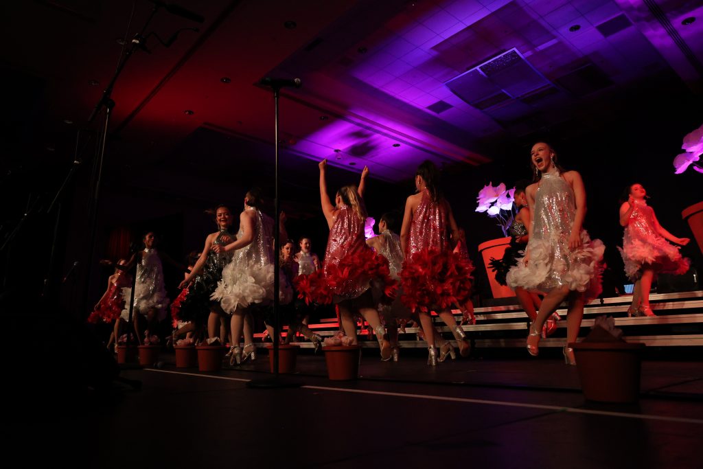 Olentangy High School She-Notes performing on stage in vibrant dresses